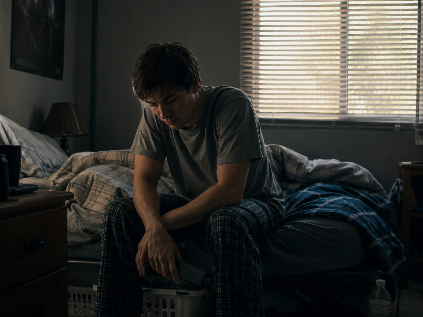 Thinking of Yours:Person sitting on a messy bed in dim morning light, looking exhausted and emotionally drained, symbolising anxiety and depression.
